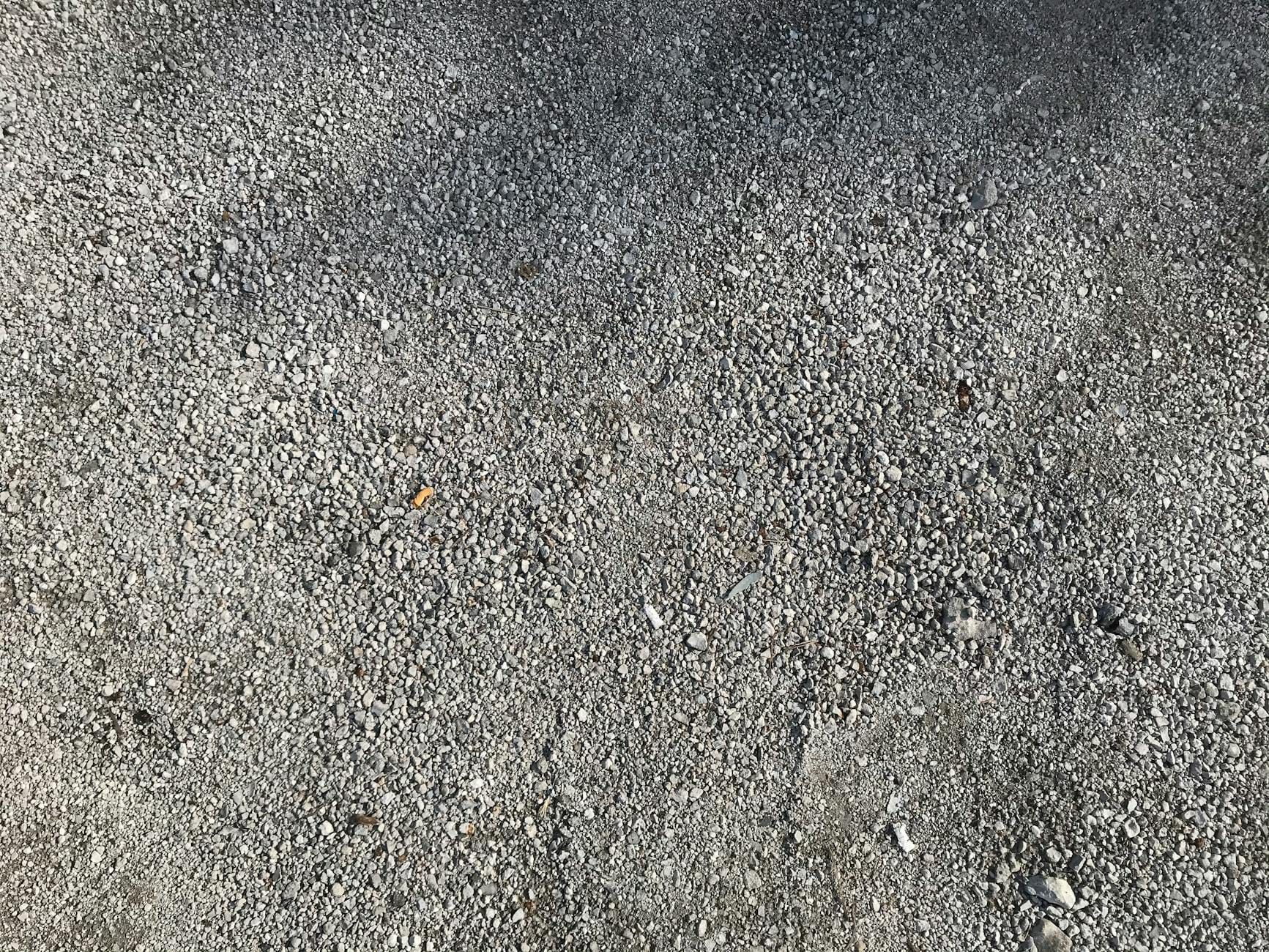 Zbliżenie szarego kruszywa betonowego na utwardzonej nawierzchni