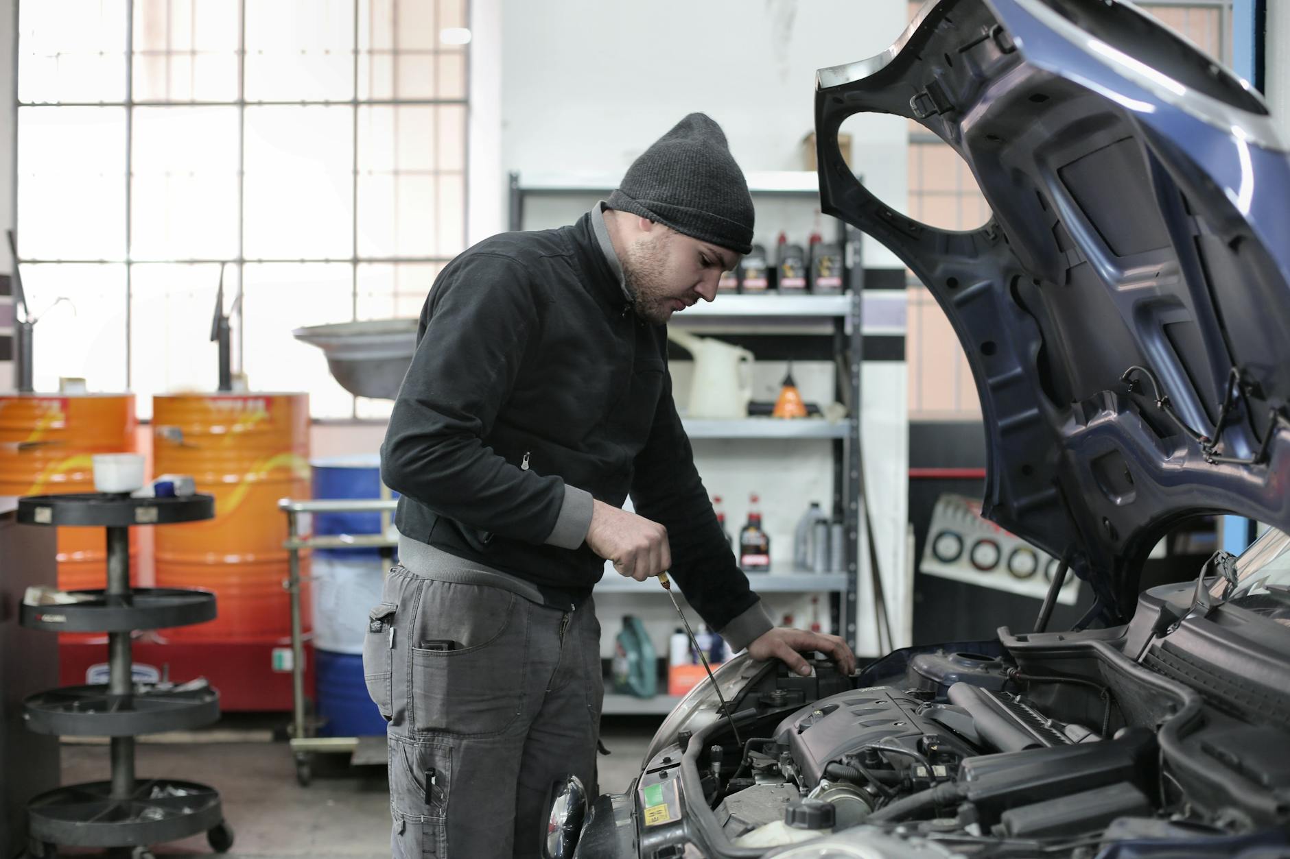 Mechanik sprawdzający silnik samochodu w warsztacie Mechanik sprawdzający silnik samochodu w warsztacie