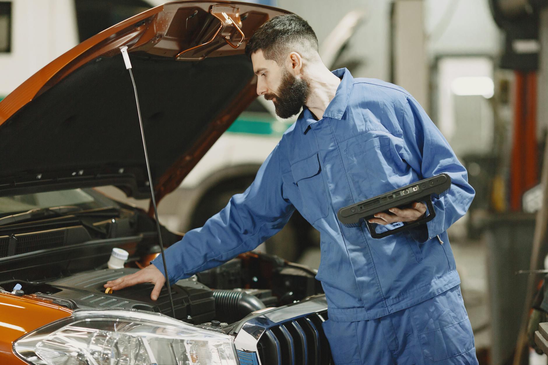 Mechanik w warsztacie sprawdza silnik samochodu pod otwartą maską