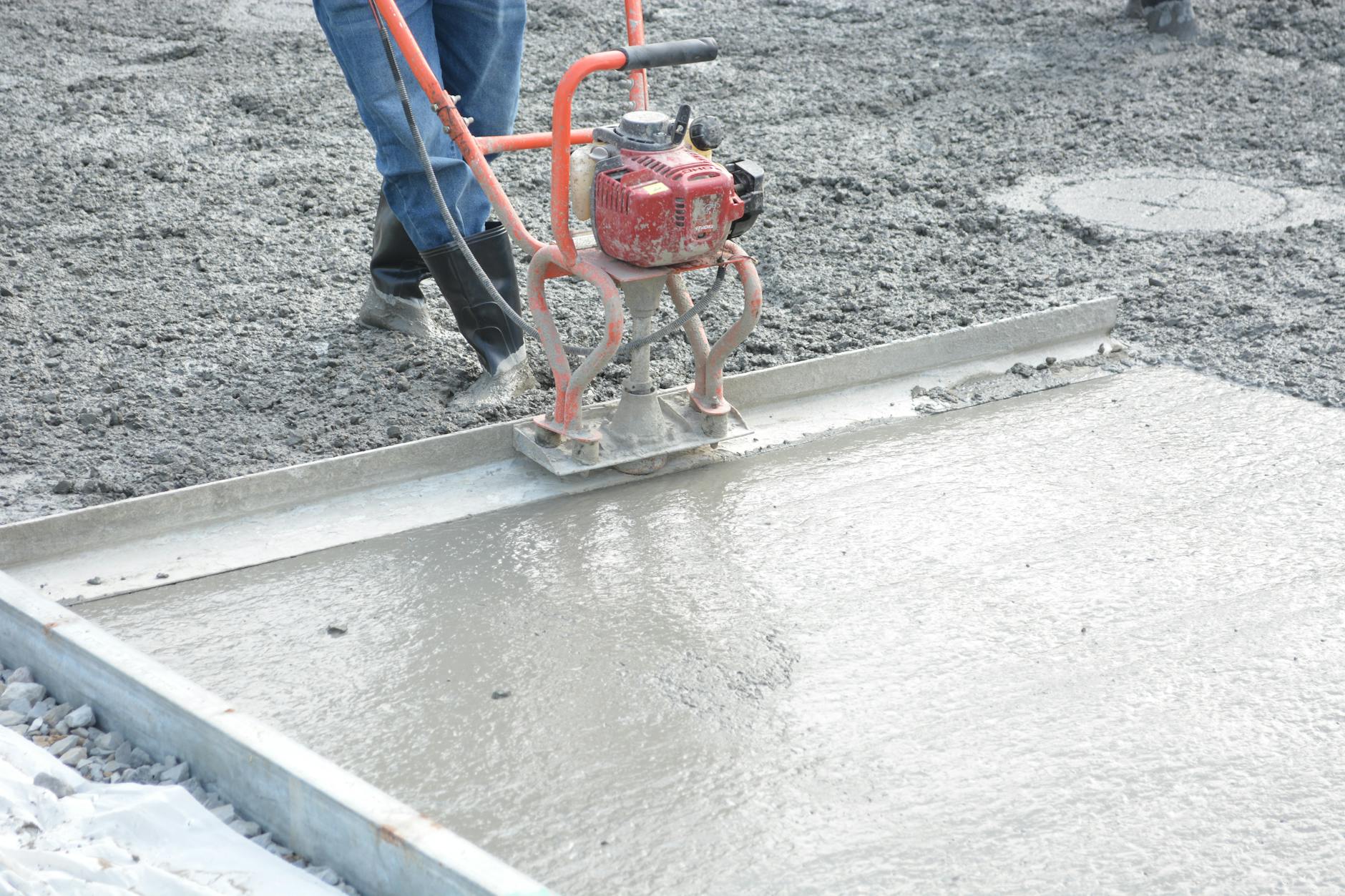 Pracownik wyrównuje świeży beton zacieraczką na budowie