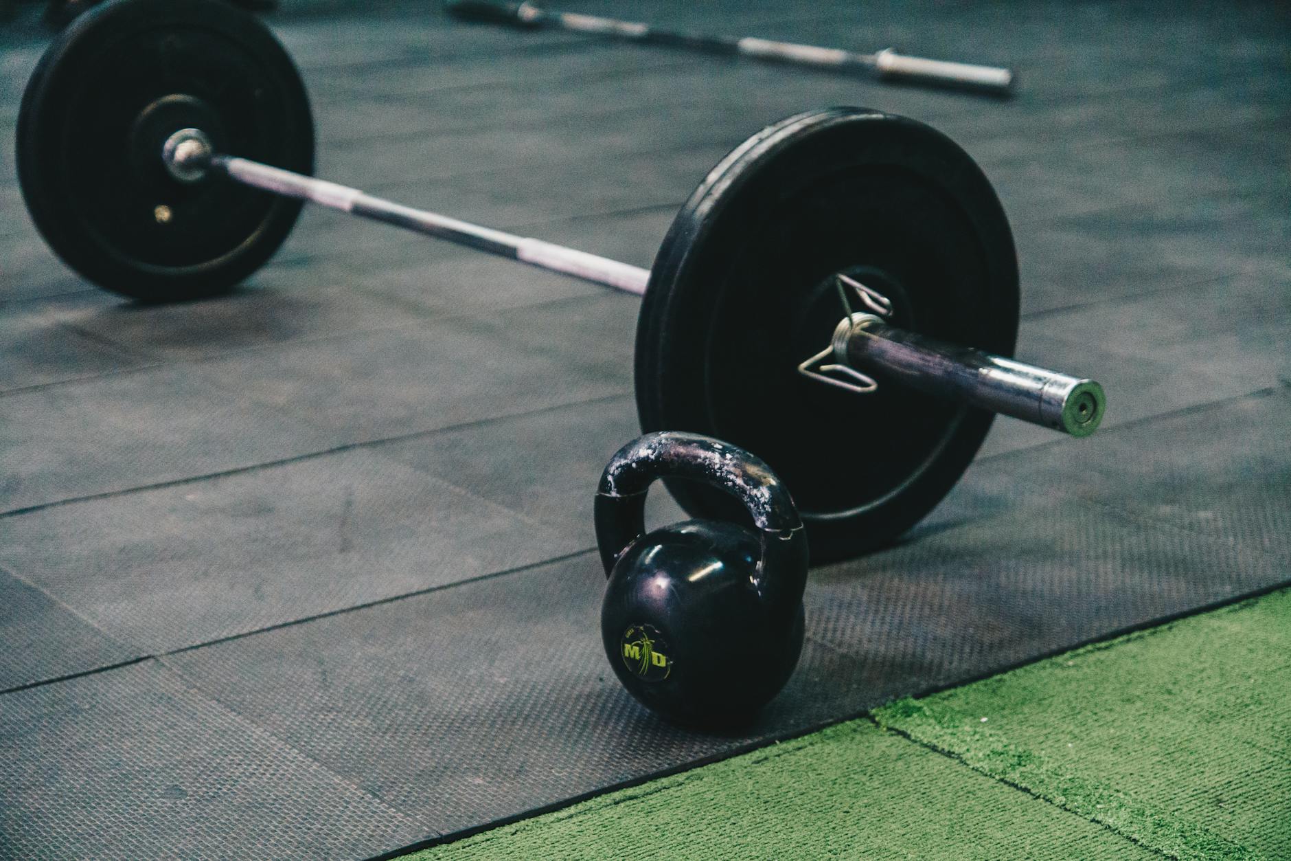 Trening siłowy dla początkujących: jak zacząć bez kontuzji i zbudować trwały nawyk Sztanga i kettlebell leżące na podłodze siłowni