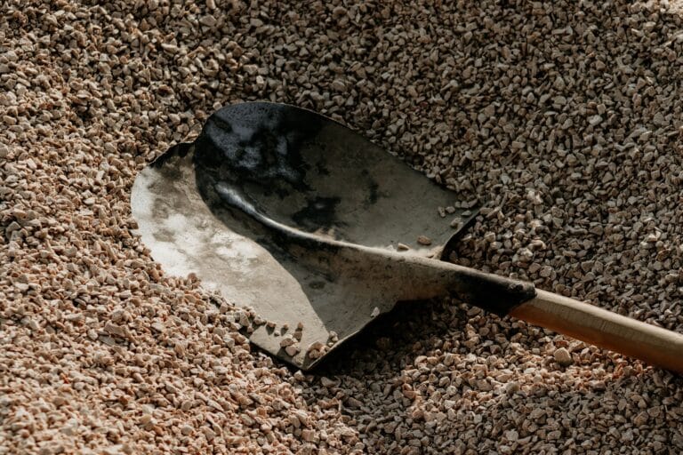 Metalowa łopata na stosie drobnego żwiru do prac wokół domu